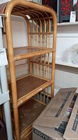 Front view of entire rattan shelf unit showing three open shelves and lower two-door cupboard
