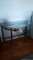 Side view of the half-moon brass and glass side table showing brass frame and glass top