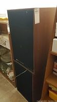 Pair of wooden JBL speaker cabinets stacked against shelving