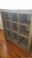 Side angle view of wooden storage unit showing nine cubbies and wood grain finish