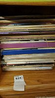 Stack of assorted vinyl record album covers, showing a variety of colors and some visible titles on the spines.