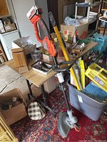 Black and Decker 20V cordless edger standing against a table with various other objects around.
