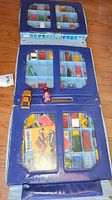 Photo showing blue multi-compartment display cases filled with various diecast cars and some cards.