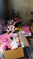 Wide view of Easter and spring faux flowers in various colors including pink and purple, with inflatables and boxes in foreground.