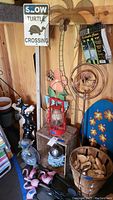 Photo of garden art including metal signs, lantern, flamingo statuette, copper yard sprinkler, gazing ball, wooden block stand, and various statuettes.