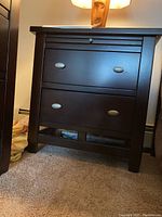 Front view of wood nightstand showing two large drawers with metal oval pulls and pull-out top shelf under lock.