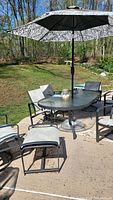 Overall view of patio dining set with table, chairs, umbrella and footrest on patio