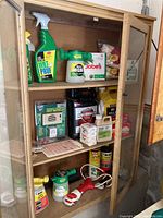 Shelved cabinet with various plant treatment sprays and pest repellents including Wilt Pruf, Jobe's fertilizer spikes, Ortho Sevin insecticide, and an Ant Shield system.
