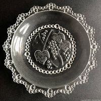 Top view of the glass bowl showing the bubble-lace scalloped edge and central etched grape leaves and grapes decoration.