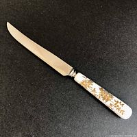Full view of the cake cutter showing stainless steel blade and gold floral bone china handle.