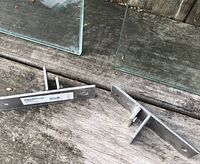 Close-up of two stainless steel Grundtal mounting brackets on wooden surface showing brackets and labels.