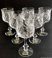 Set of six Lausitzer crystal wine glasses arranged in a group, showing details of cut patterns and original stickers on the bases.