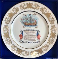 Full view of plate in presentation box showing gold gilt scroll border and central image of Mayflower with inscriptions.