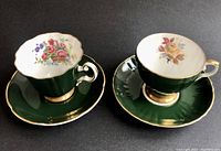 Pair of vintage Royal Grafton tea cups and saucers showing floral interiors and gold trim on dark green glaze
