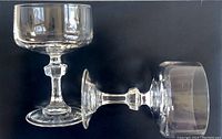 Side and upright view of one clear crystal cordial glass with hexagonal stem knob on a flat base showing detailed shape and design.