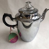 Side view showing the mirror chrome finish aluminum body, black Bakelite handle, and original tag hanging from handle.