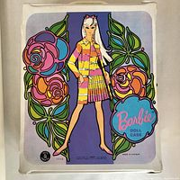 Front of vintage Barbie doll case showing mod Barbie artwork and colorful 1960s floral design with 'Barbie Doll Case' text. Case shows minor wear.