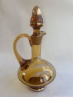 Full image of amber glass decanter showing shape, handle, stopper, and gold accents.