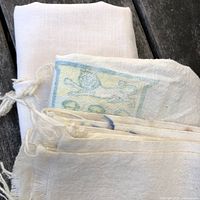 Folded vintage flour sacks showing one plain bleached and one with blue printed design.