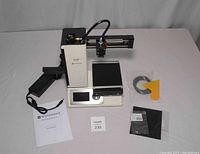 Printer and accessories laid out on table, showing main unit, power supply, cables, manual and lot tag