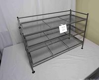 Front side view of the metal shoe rack with three mesh shelves, showing the overall structure and design.