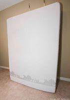 Front view of the Douglas queen size mattress standing upright against a wall on carpeted floor. Shows fabric pattern and clean surface.