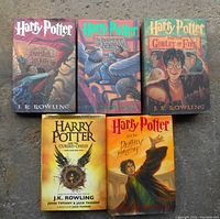 Photo of five hardcover Harry Potter books arranged on a flat surface showing front covers.