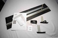 Top view of the Logan mat cutter with instruction manual and three handles displayed on a white surface.