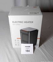 Photo of electric heater in its original white box labeled "ELECTRIC HEATER DH-QN02" showing front and side views of packaging.