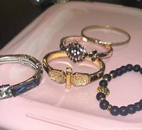 Photo showing five bracelets with different materials and designs placed on a tray.