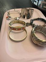 Photo showing six assorted fashion bracelets on a pink tray