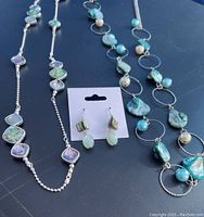 Lot contents showing two gemstone necklaces and a pair of earrings arranged on dark surface.