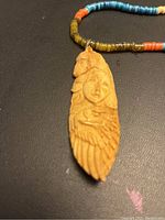 Close up of the hand carved pendant showing detailed face and eagle motifs.