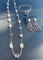 Full lot of rose quartz and amethyst jewelry on surface showing necklace, earrings on card, and bangle bracelet