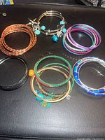 Six sets of assorted bracelets including braided bangles, charm bangles with beads, enamel and mixed metal bangles.