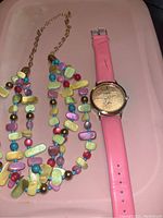 Full kit showing the pink strapped wristwatch and colorful beaded necklace