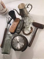 Wide view of assorted antique items including clock, bottles, teapot, mallet, glassware and wooden box