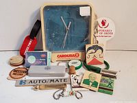 Full group view showing all vintage advertising collectibles including clock, airline memorabilia, poker chips, matchbooks, and more.