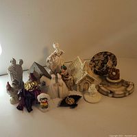 Photo showing the full lot of 15 vintage ceramic and decorative items arranged on a white surface against beige background. Items include figurines, small houses, bird figurines, and ashtray.