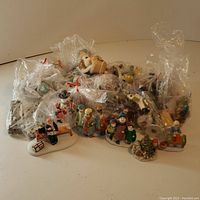 Wide shot of multiple ceramic Christmas figurines and ornaments, some packed in plastic bags and some displayed in front.