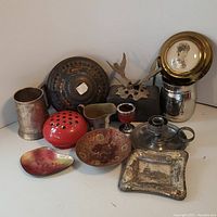 Full group of 13 assorted vintage metal and tin decorative pieces including trays, pitchers, candlesticks, ashtray, and advertising tins, all showing varying degrees of wear.