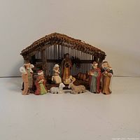 Front view of the vintage nativity set showing all figures arranged in front of the wooden manger stable.