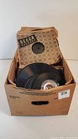 Box containing multiple vintage 78 RPM records in worn Decca branded paper sleeves showing signs of age and wear.