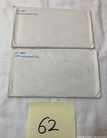 Two white sealed envelopes labeled 'U.S. Mint 1975 Uncirculated Coin' containing the coin sets.