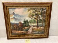 Framed oil painting showing a dirt road through trees and bushes with mountains in the background, artist signed.