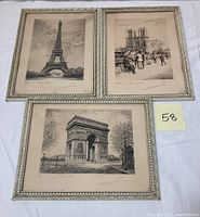 Photo showing the three framed etchings depicting the Eiffel Tower, Notre Dame with bouquinistes, and Arc de Triomphe, all framed in whitewashed frames.