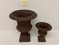 Both urns side by side showing relative sizes and rust patina