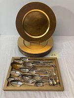 Seven gold-tone charger plates stacked with one displayed upright.