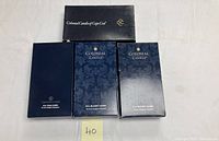 Top view of three boxes of Colonial Candle Cape Cod candles, two labeled Wm. Hammond's Scent, one plain dark blue box with branding.