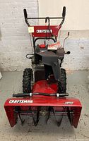 Full front view of red Craftsman snow blower showing handles, engine and intake housing.